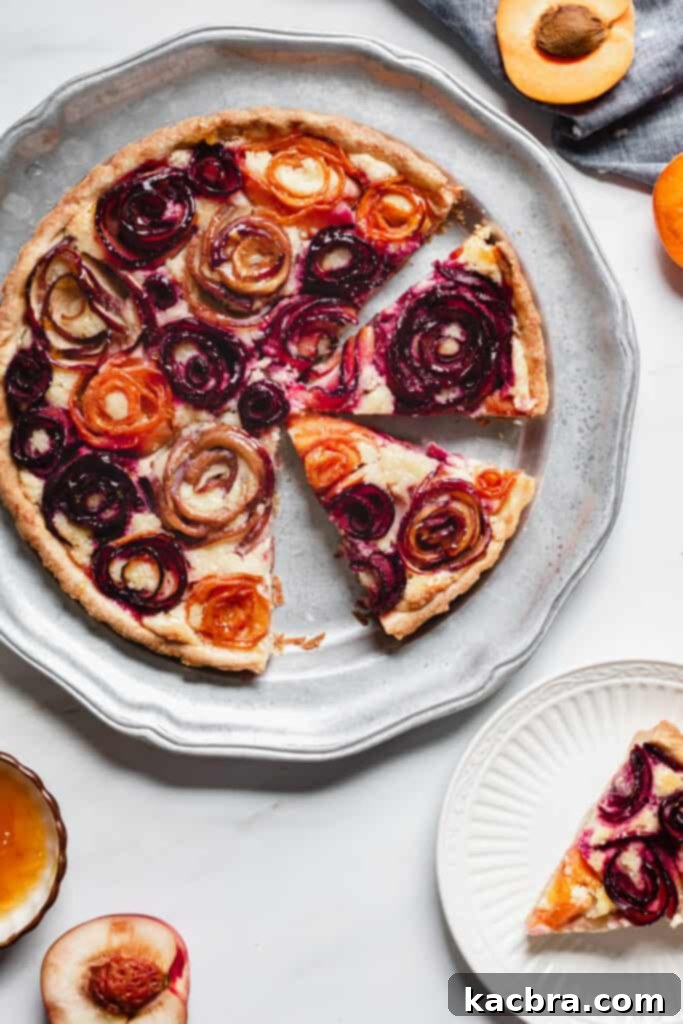 Baked stone fruit tart shot from overhead with one slice removed, revealing the delicious frangipane and fruit layers.