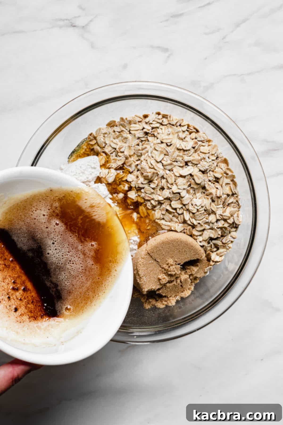 Brown butter being poured into a bowl containing sugar, oats, and flour for the crisp topping.