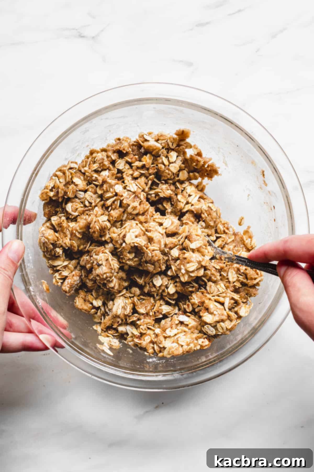 The brown butter, sugar, flour, oats, and spices being mixed together with a spoon to form crumbles for the topping.