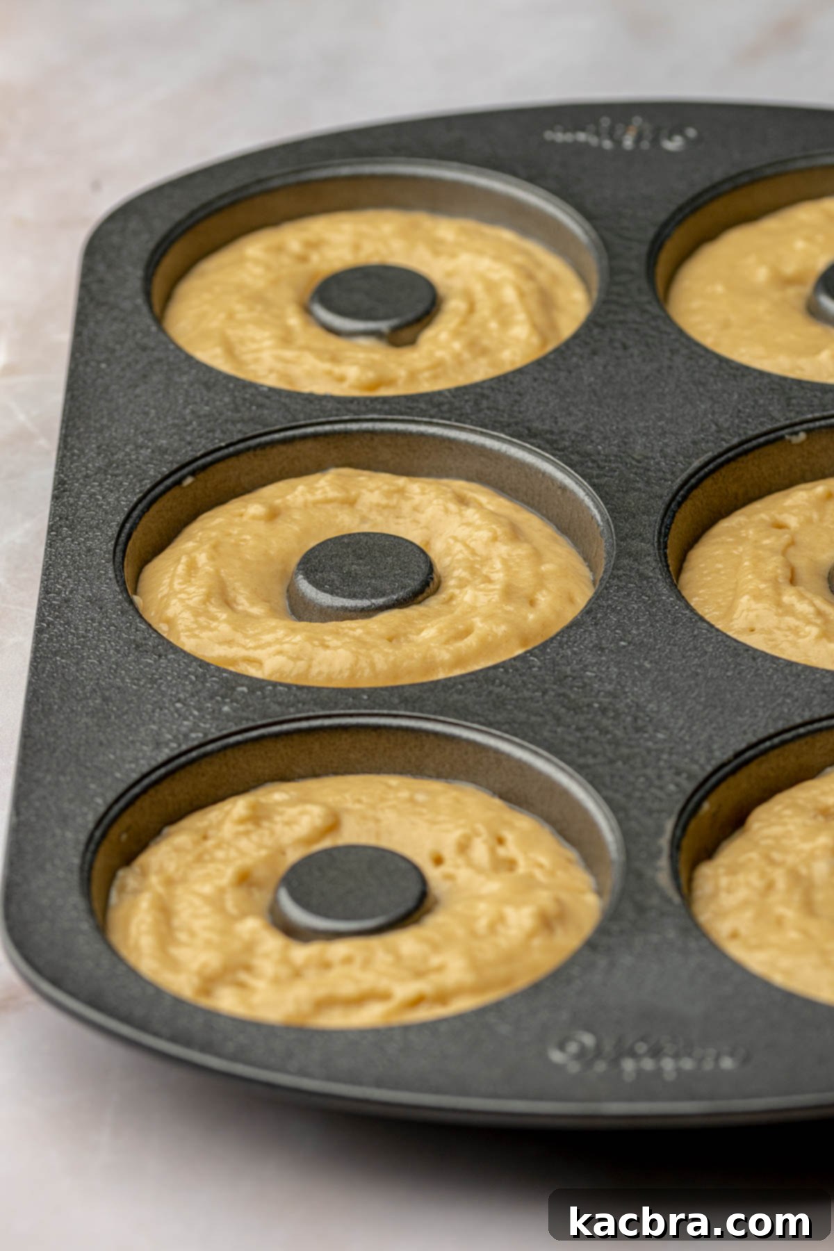 Filled donut pan with batter before baking, showing the correct fill level.