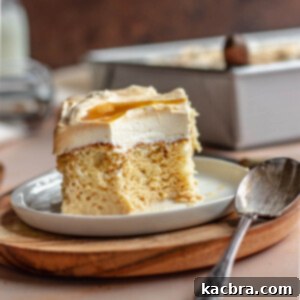A piece of tres leches cake on a plate with a bite removed and the spoon resting on the plate.