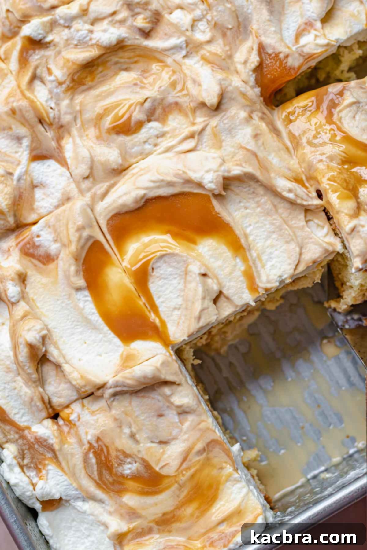 Close up view of a caramel tres leches cake with several slices removed, revealing the moist interior and swirled caramel topping.