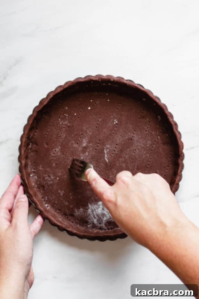 Chocolate tart shell lined with parchment paper and pie weights