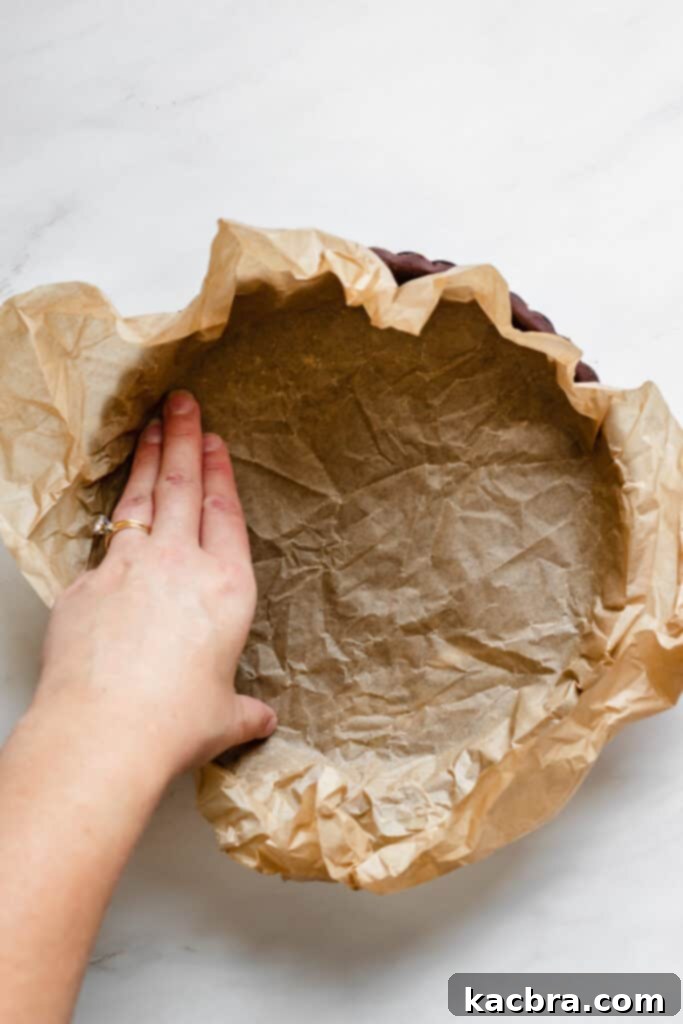 Placing parchment paper into the chocolate tart shell