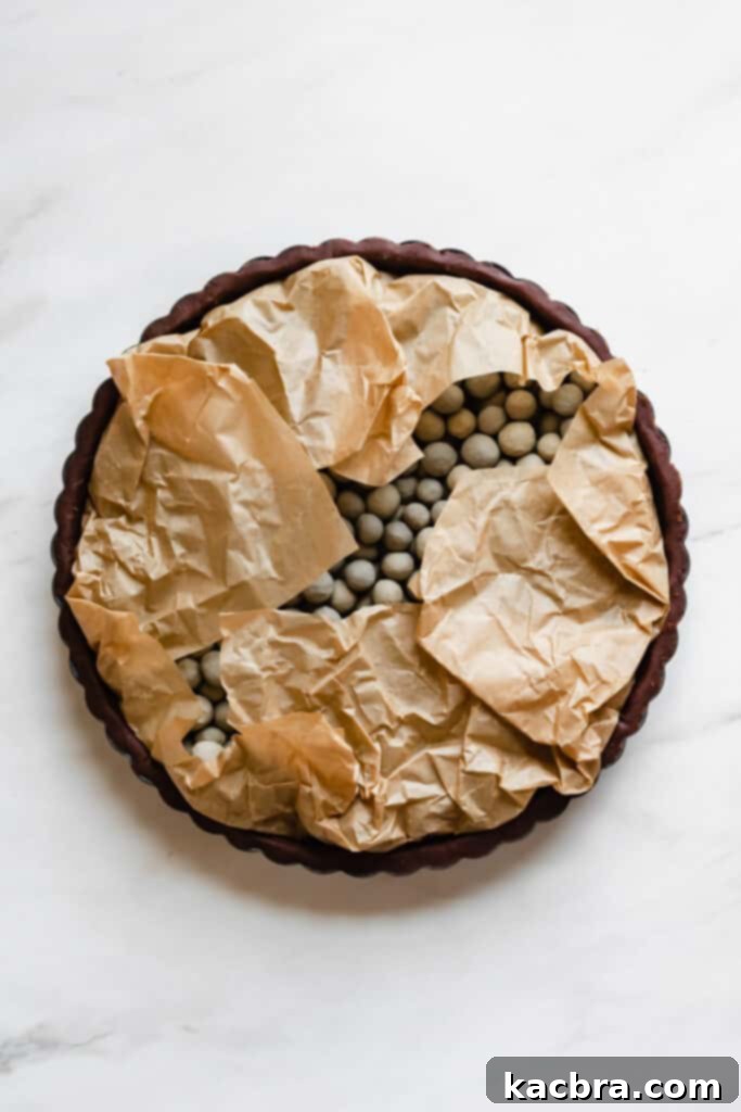 Folding parchment paper over pie weights in tart shell