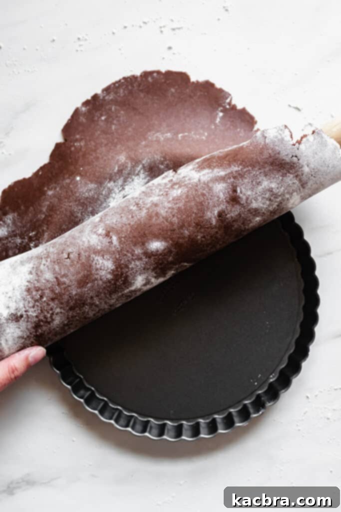 Rolling chocolate tart dough onto a rolling pin for transfer