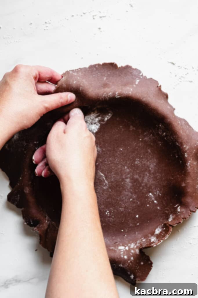 Unrolling chocolate tart dough over the tart pan