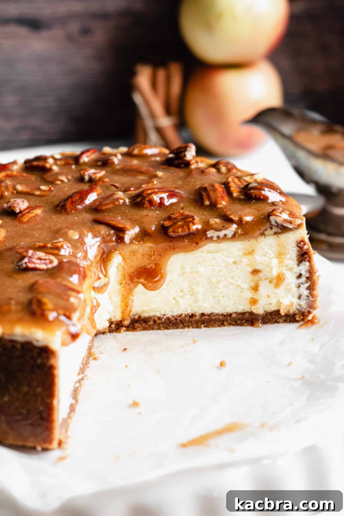 Decadent Caramel Pecan Cheesecake 2 A cross-section of the creamy New York-style cheesecake, showing the graham cracker pecan crust and the rich apple cider caramel pecan sauce generously dripping down its sides.