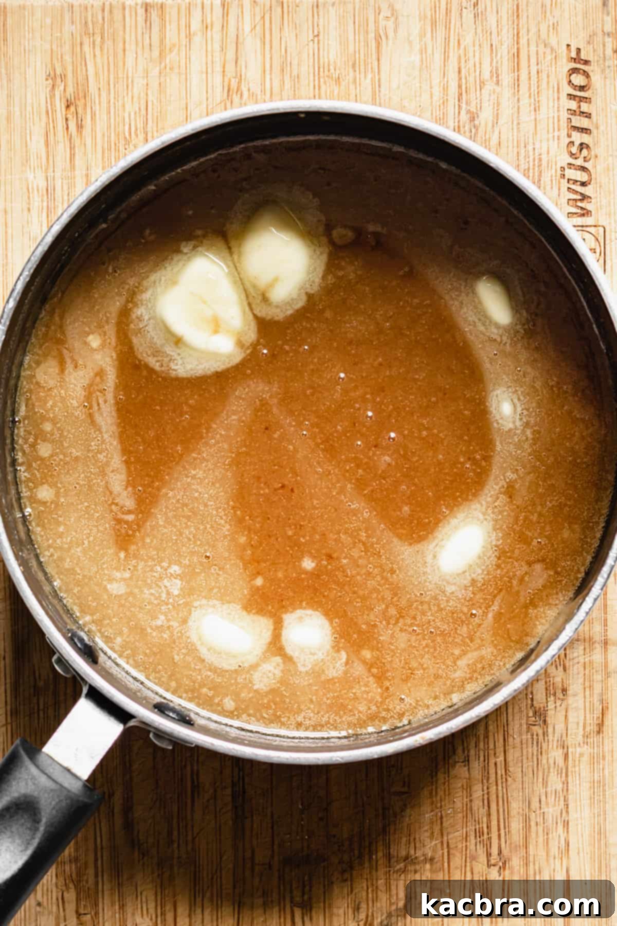 Decadent Caramel Pecan Cheesecake 13 The caramel mixture gently melting and combining in a saucepan, with visible bits of butter being incorporated.