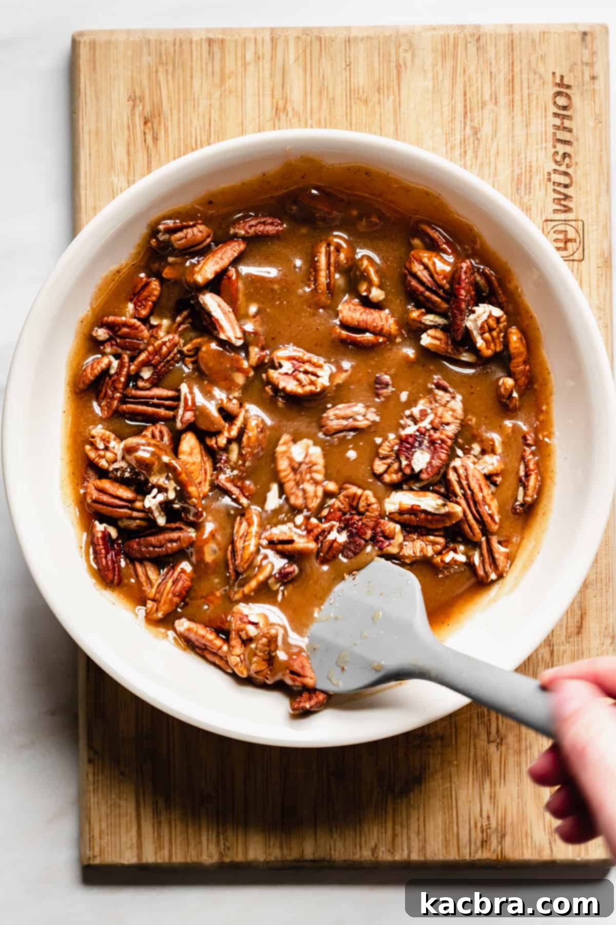 Decadent Caramel Pecan Cheesecake 15 Toasted pecans being stirred into the finished apple cider caramel sauce, adding texture and nutty flavor.