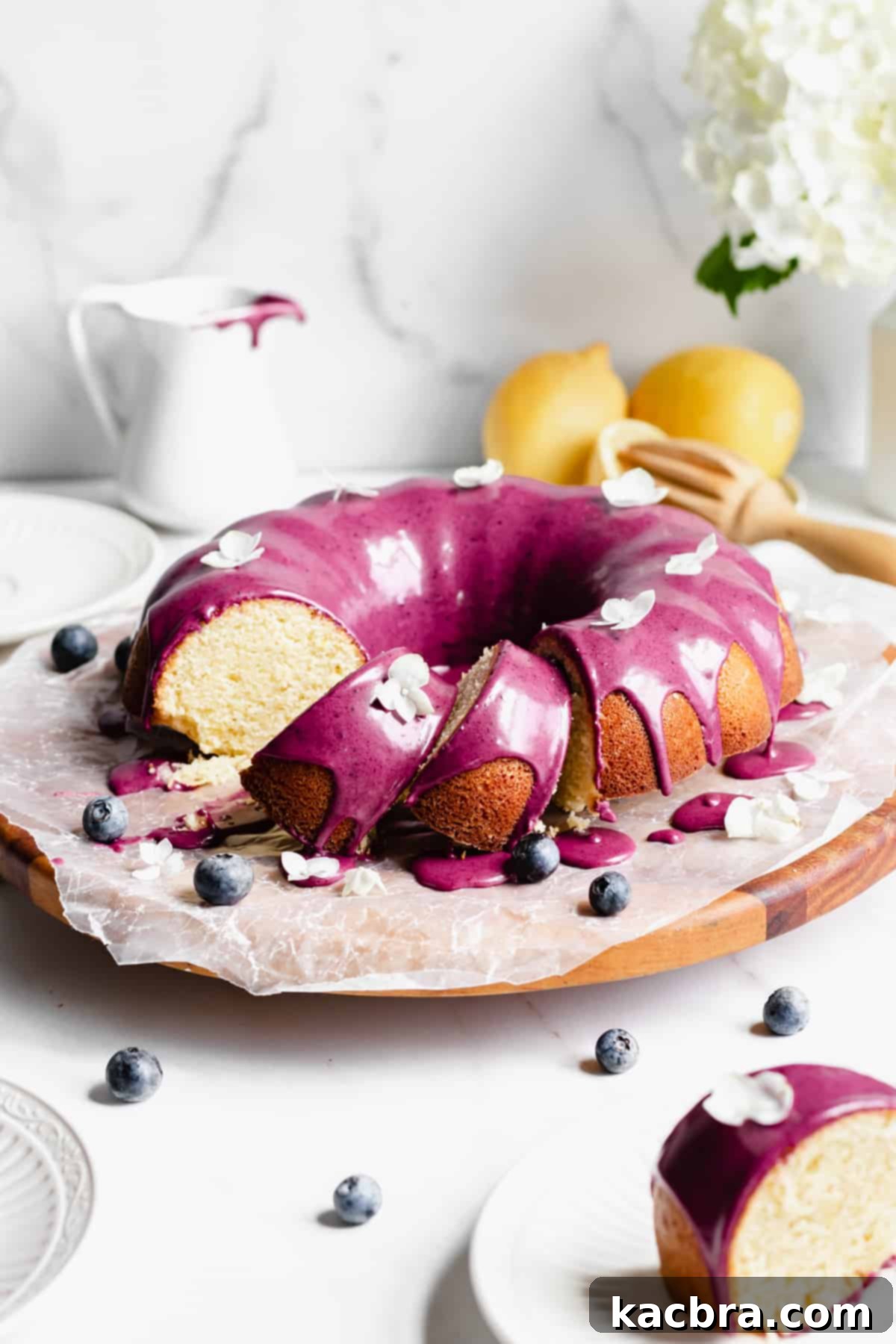 Velvet Lemon Ricotta with Bursting Blueberry Glaze 9 A beautifully presented lemon pound cake on a platter with a few inviting slices arranged nearby.