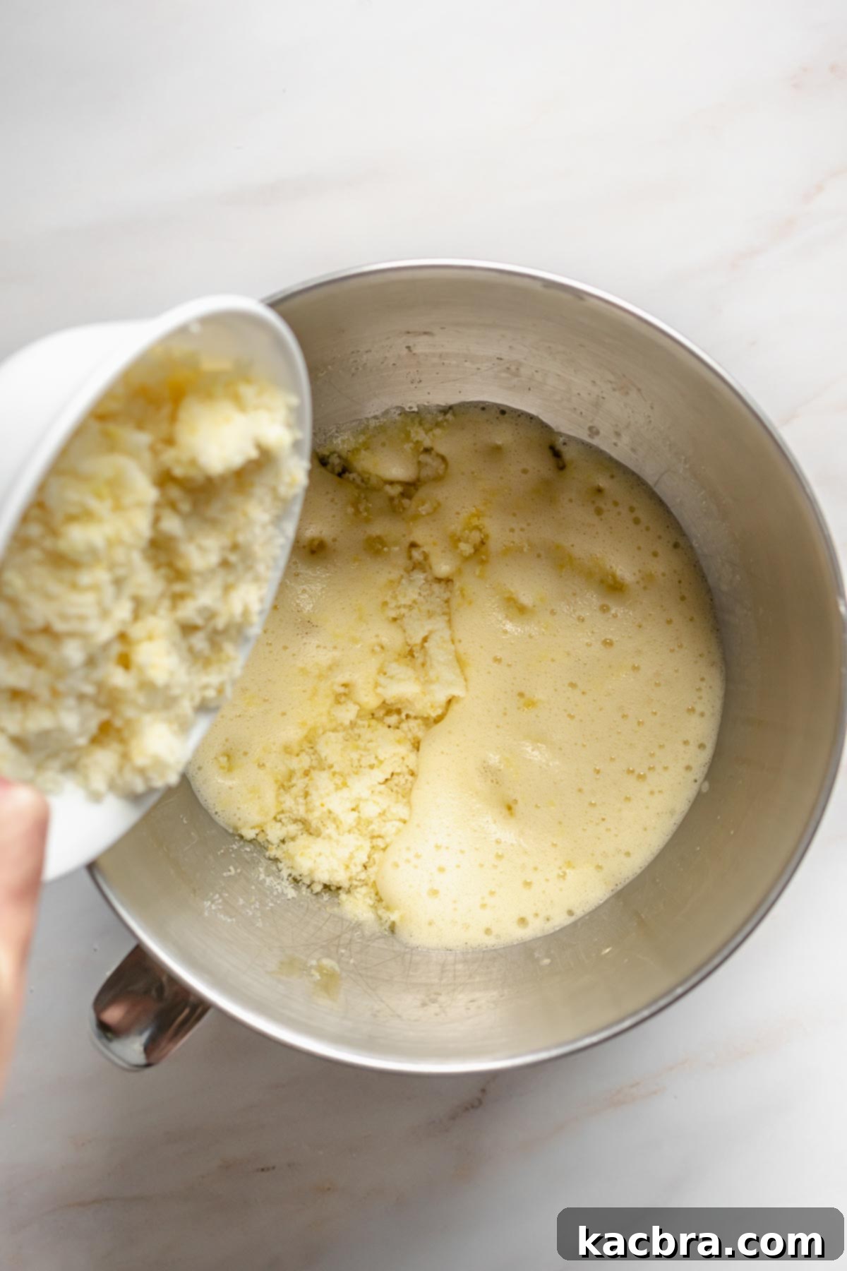 Velvet Lemon Ricotta with Bursting Blueberry Glaze 4 Lemon zest sugar pouring into whipped eggs, creating a vibrant mixture for the cake batter.
