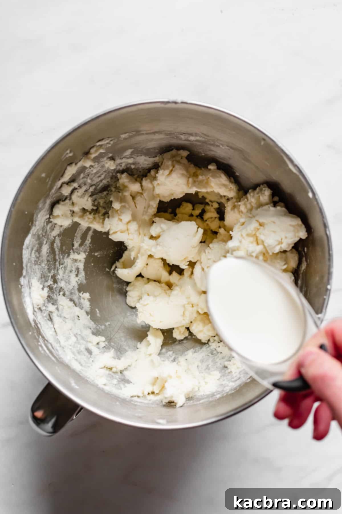 Heavy cream being added to the buttercream.