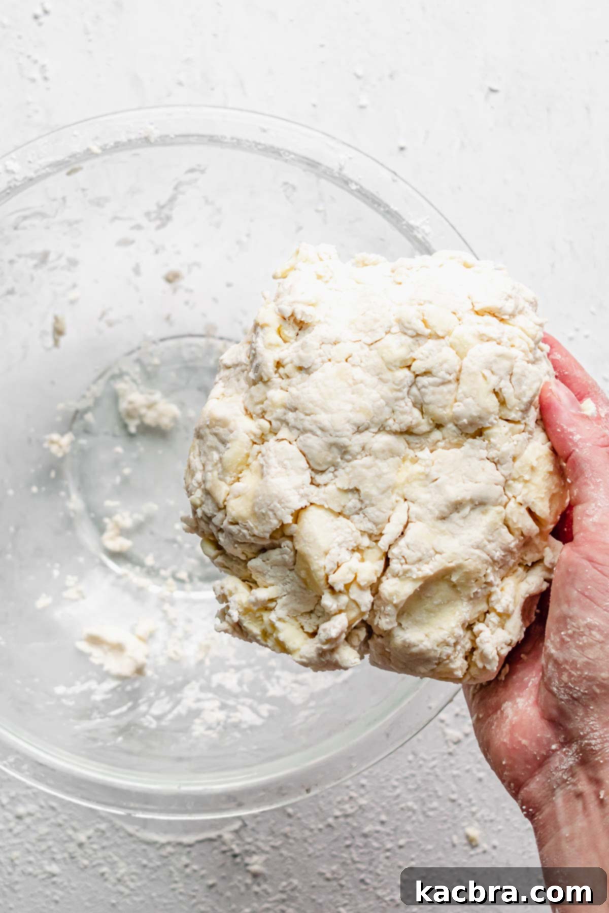 A hand gently squeezing the dough, demonstrating the test for readiness where it holds together.