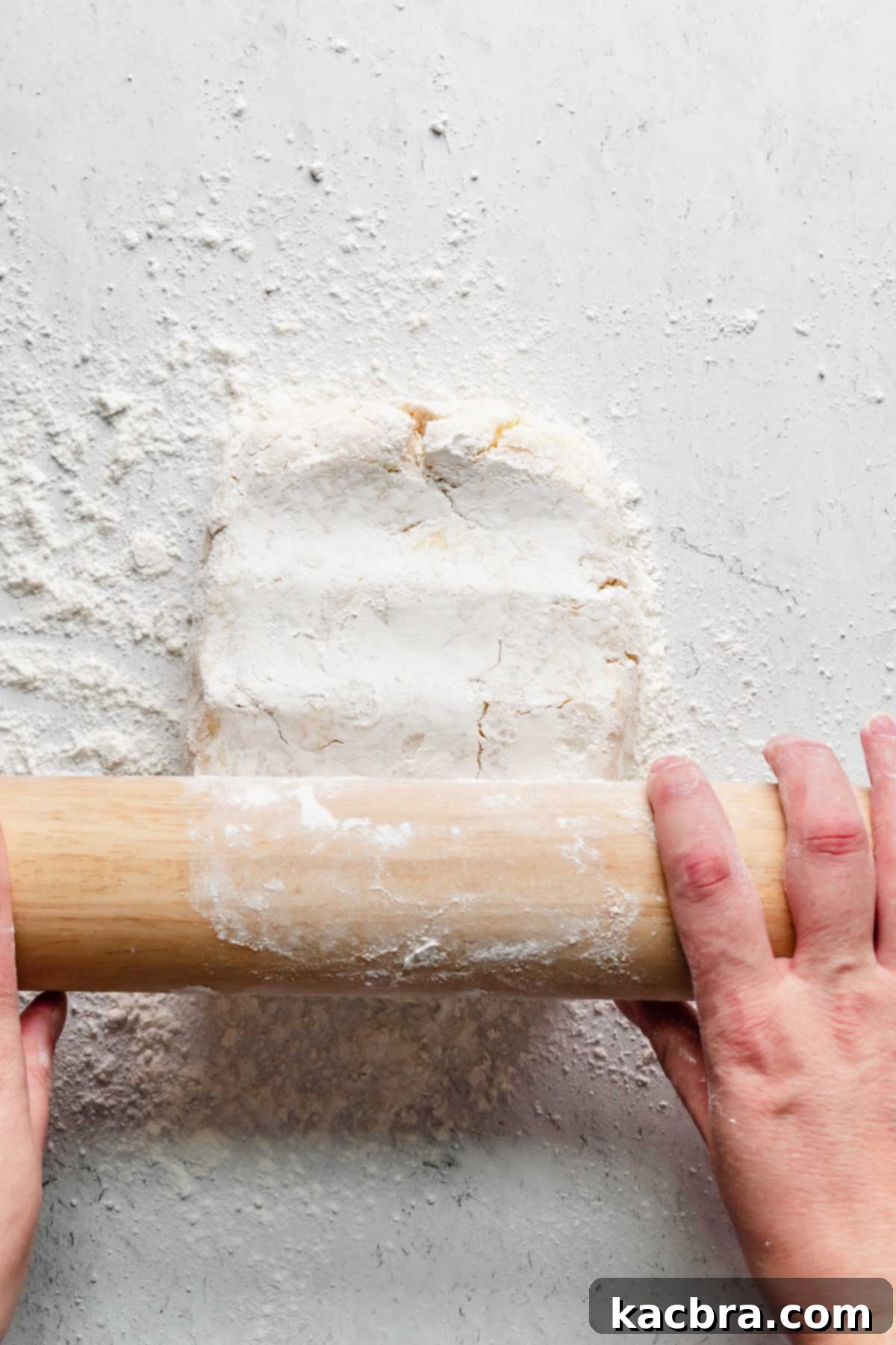 A floured rolling pin beginning to roll out the dough on a lightly floured surface.