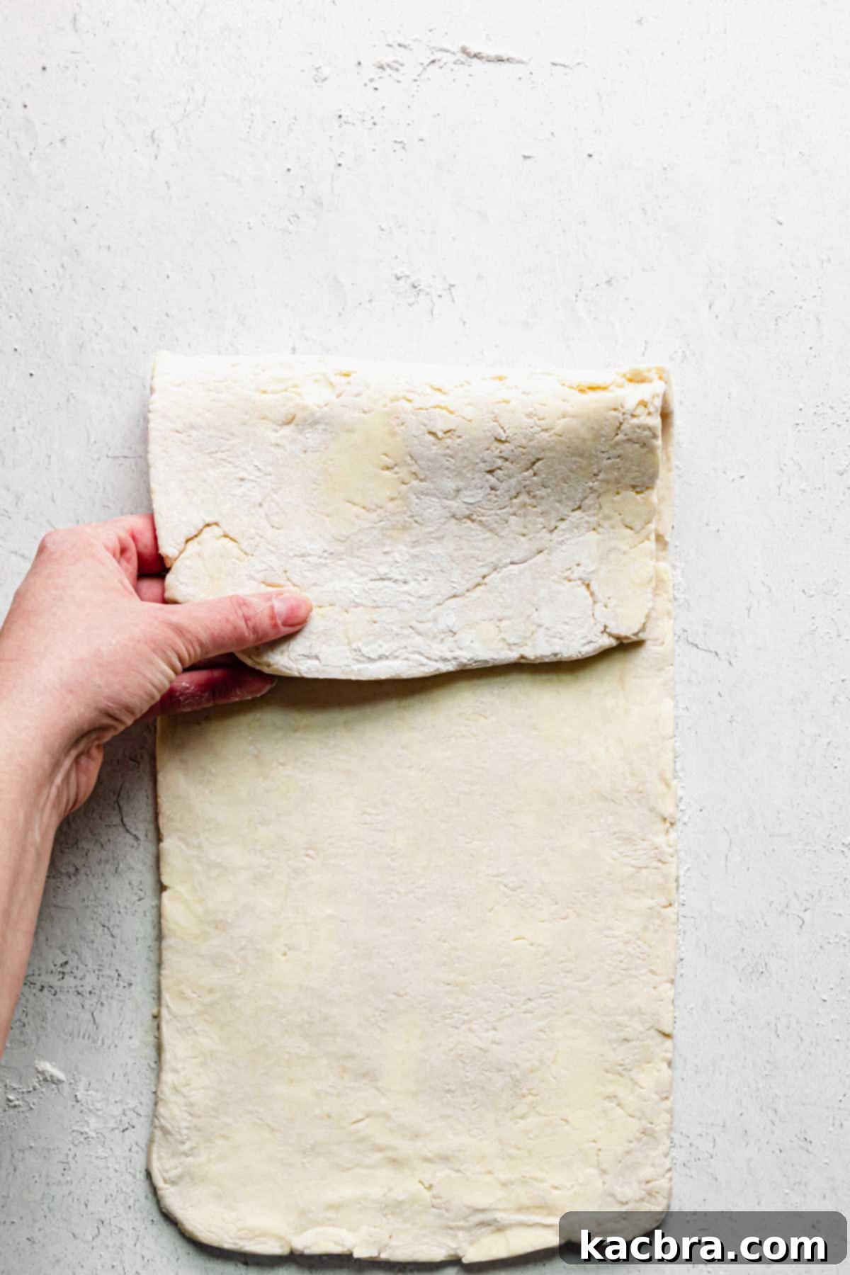 A hand folds the top of the pastry down to half.