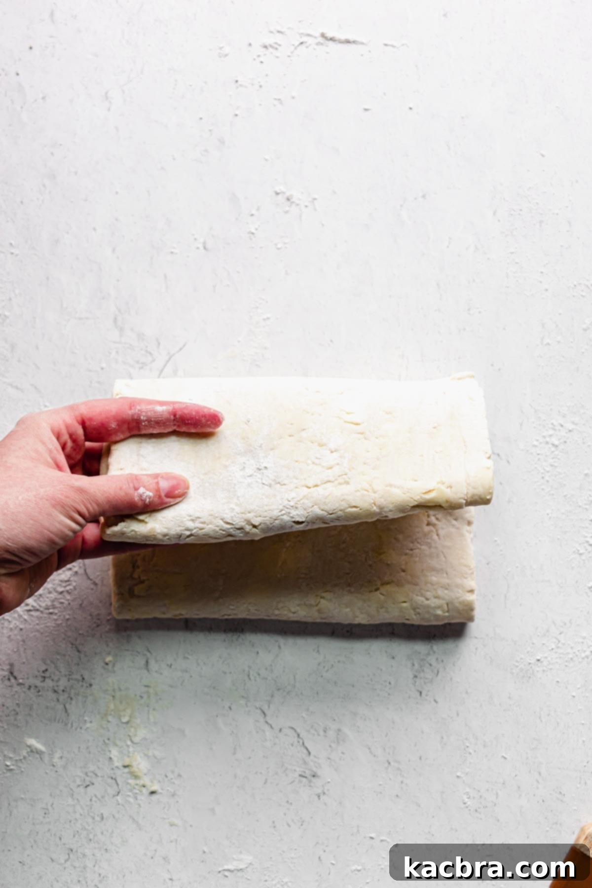 A hand completing the book fold by bringing the two halves together, as if closing a book.