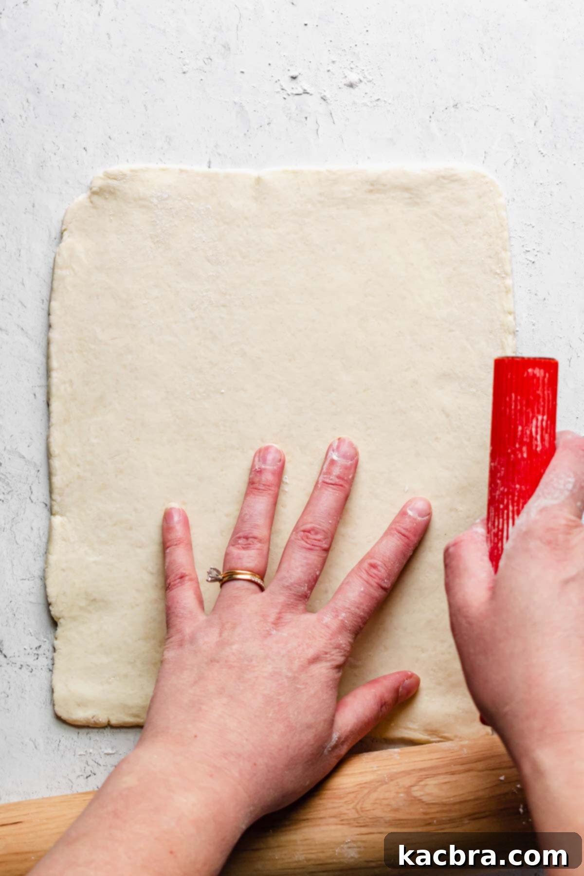 One half of the pastry rolled out with a bench scraper shaping the sides.