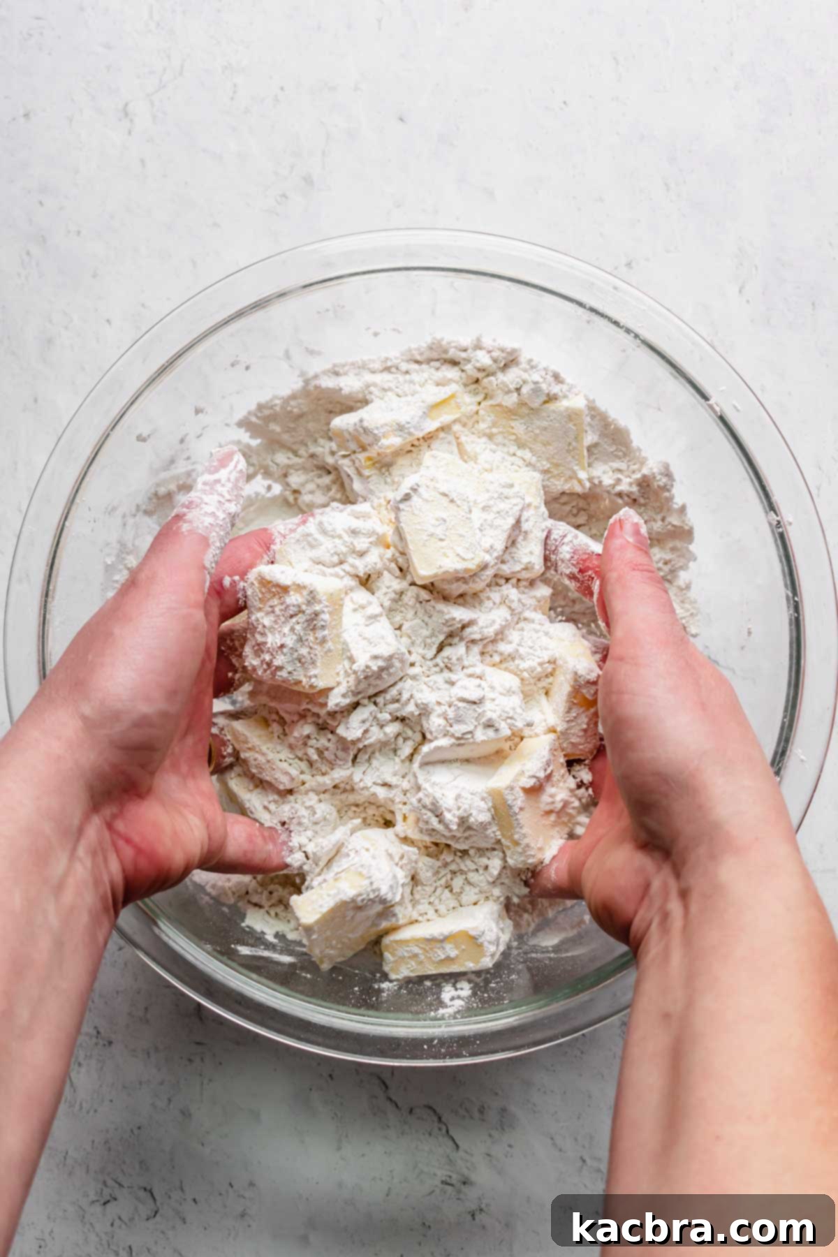 Hands toss the flour and butter together.