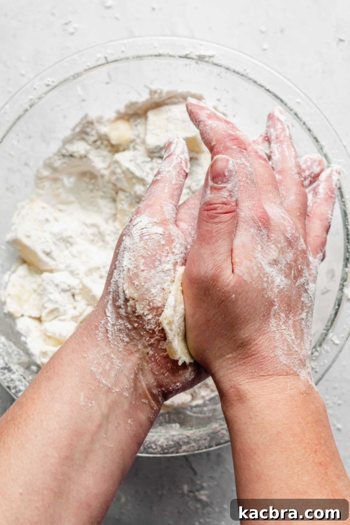 Flattening a piece of cold butter between the palms of two floured hands.