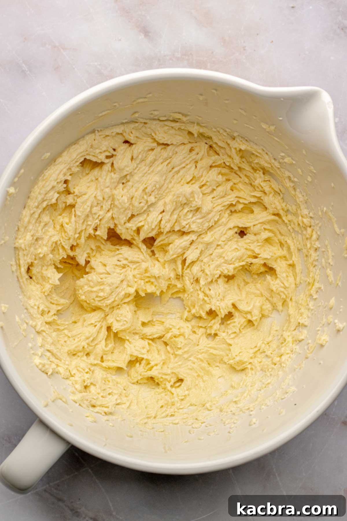 Creamed butter and sugar in a bowl with track marks from the mixer, showing a light and fluffy texture.