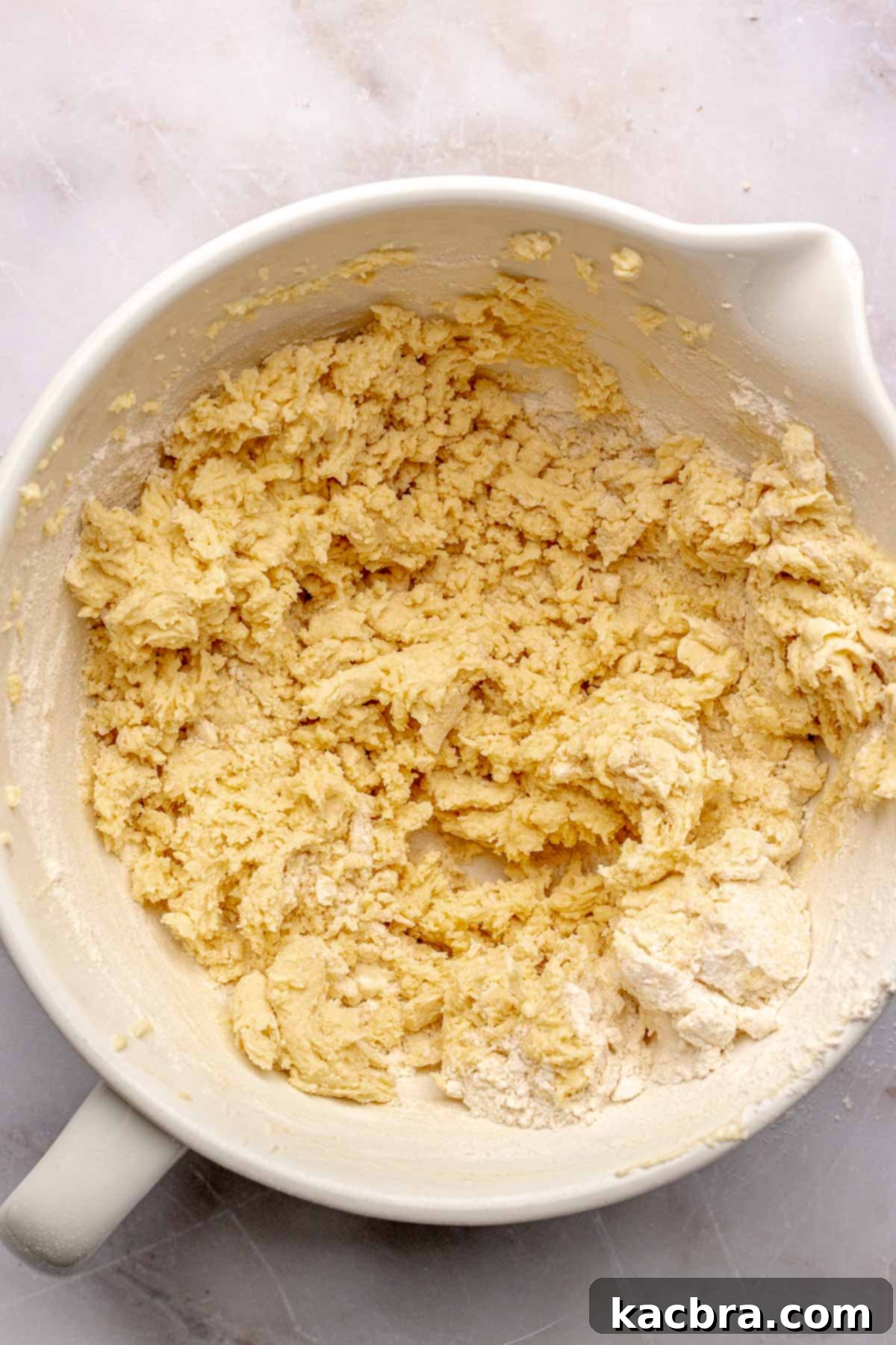Shortbread cookie dough in a bowl, appearing cohesive and slightly crumbly.