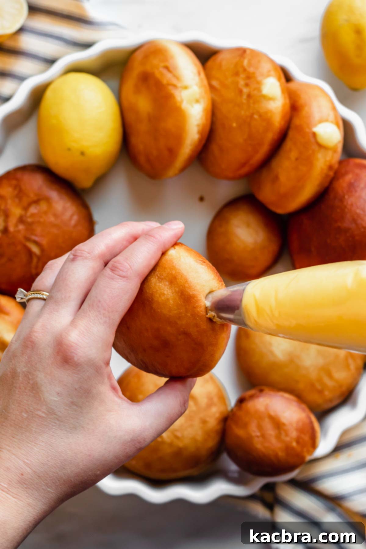 Zesty Meringue Cloud Donuts 14 Lemon curd being piped into a fried donut.