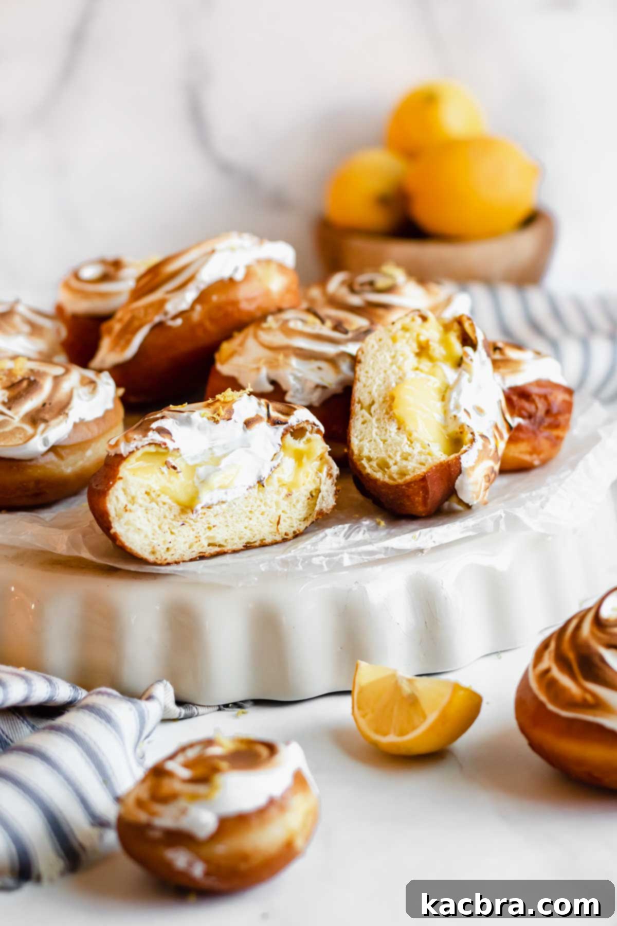 Zesty Meringue Cloud Donuts 17 Straight on shot of a pile of lemon donuts, one is split open.