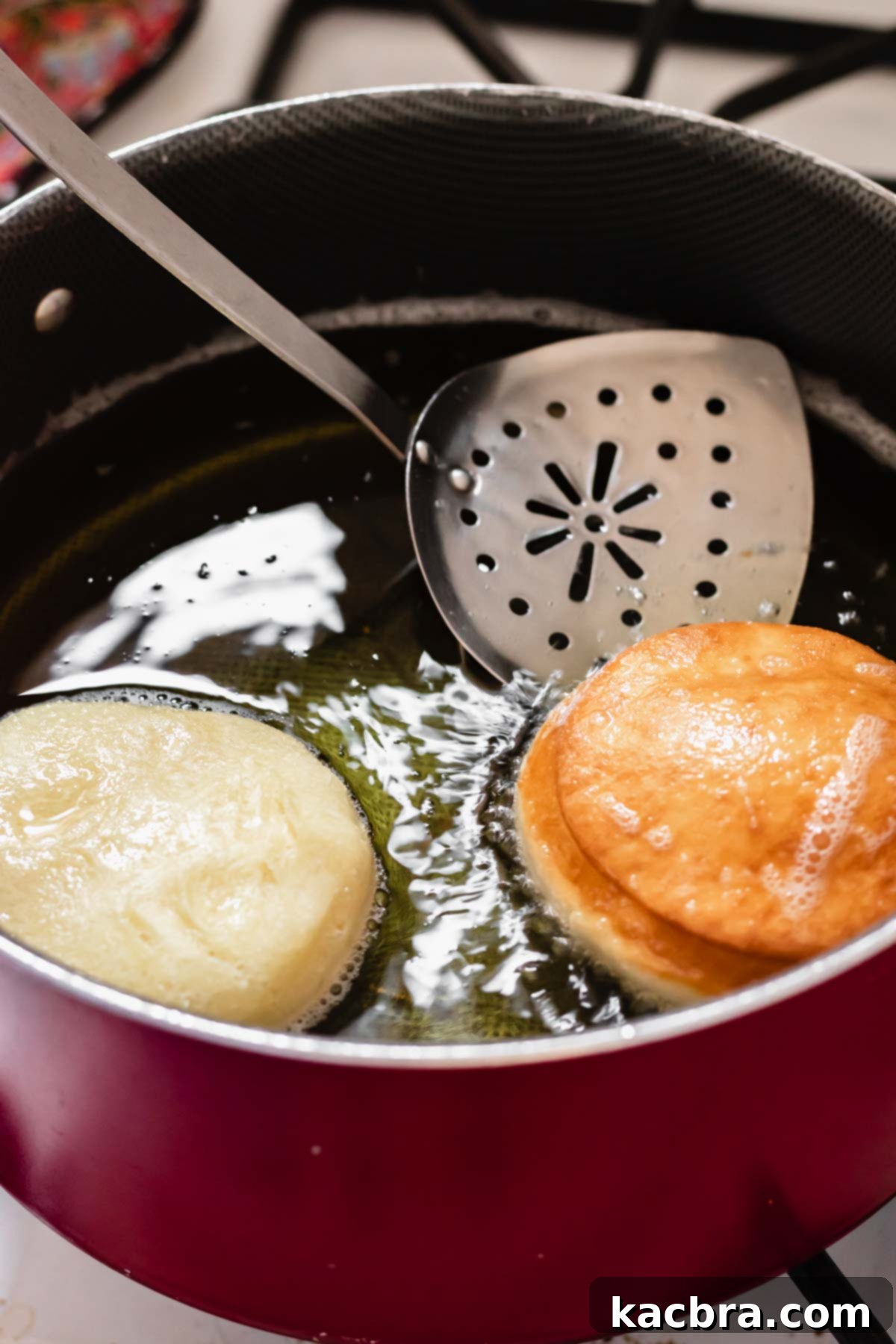 Zesty Meringue Cloud Donuts 10 Donuts in a pot of oil getting fried. One has just been flipped to show the golden color.