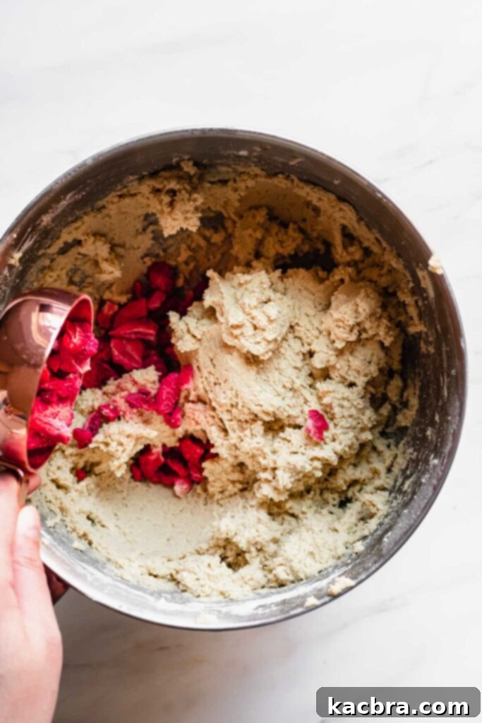 Freeze dried strawberries being gently mixed into the cookie dough, ready for shaping.