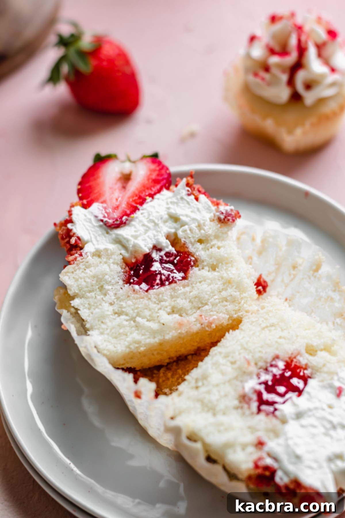Double Strawberry Crunch Cupcakes 3 A strawberry crunch cupcake expertly sliced open, showcasing the rich strawberry jam filling nestled within its moist vanilla cake.