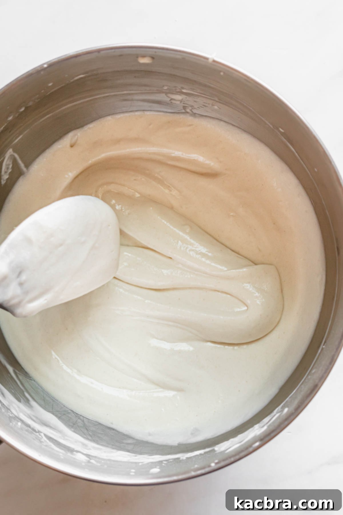 Double Strawberry Crunch Cupcakes 9 A spatula gently pulls through the finished vanilla cupcake batter, revealing its thick, airy, and ribbon-like consistency, perfect for baking.