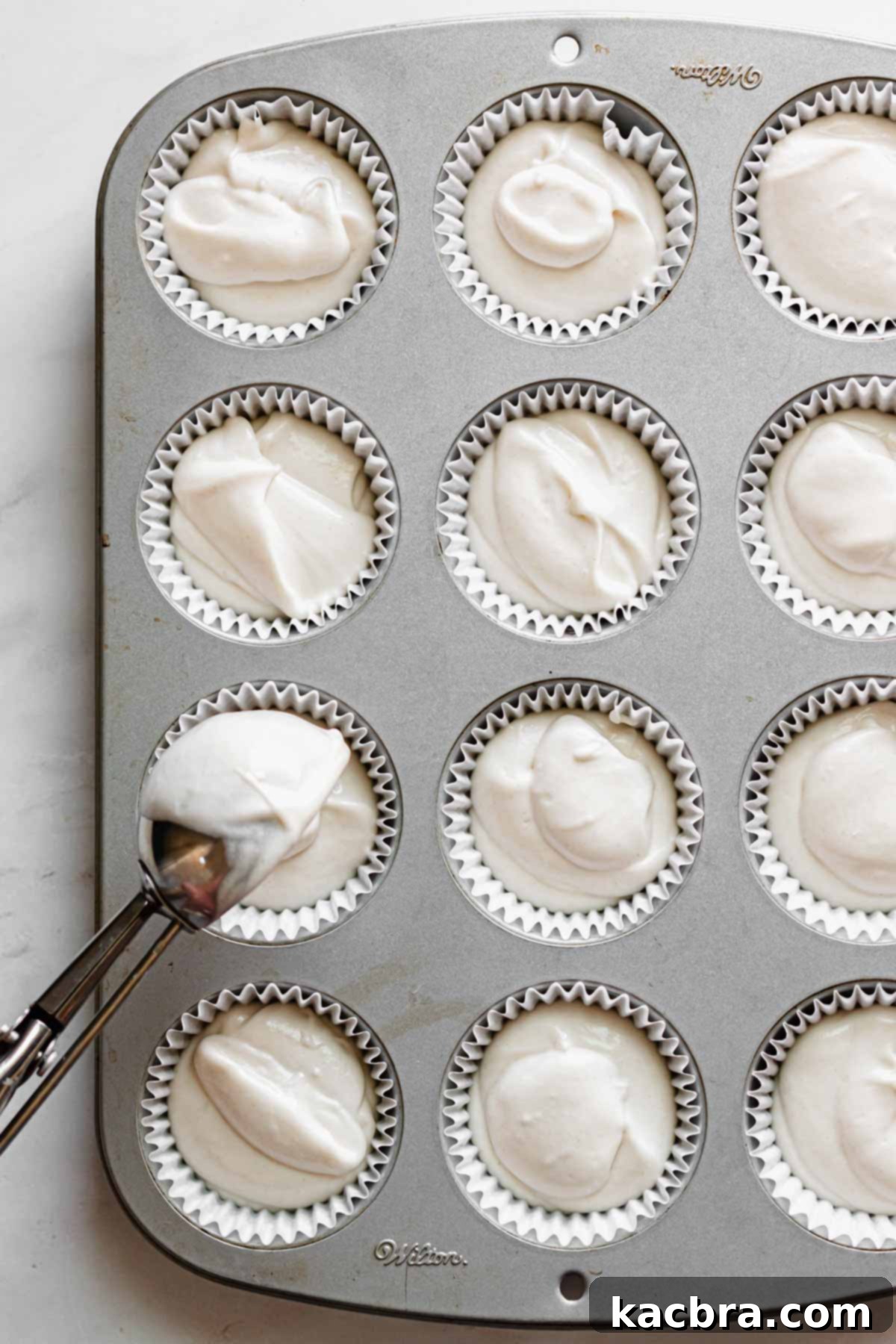 Double Strawberry Crunch Cupcakes 10 Vanilla cupcake batter being meticulously scooped into cupcake liners, ensuring each is two-thirds full for optimal baking.