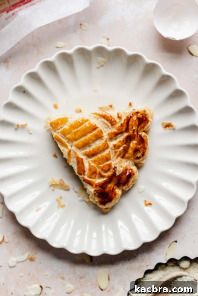 Overhead shot of one perfect slice of Galette des Rois on a white plate, highlighting its layers and filling.