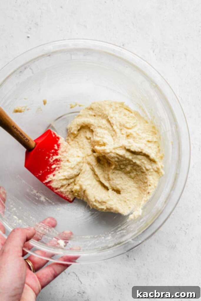 A spatula rests in a bowl, showcasing the perfectly smooth and creamy almond frangipane.
