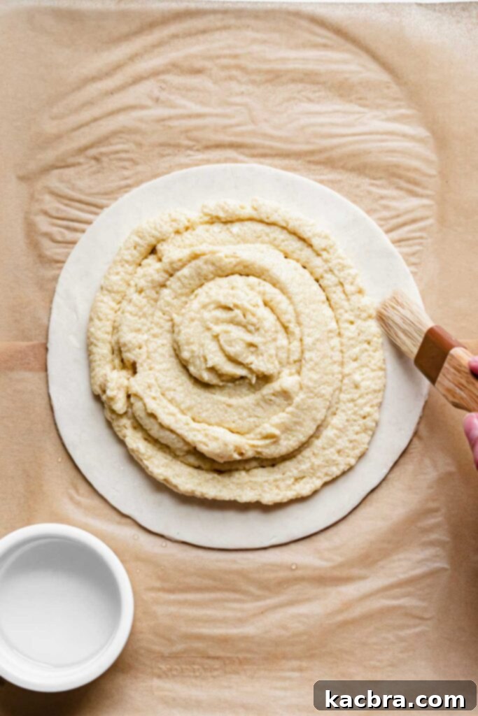 A pastry brush applies a thin layer of water to the exposed pastry edges.