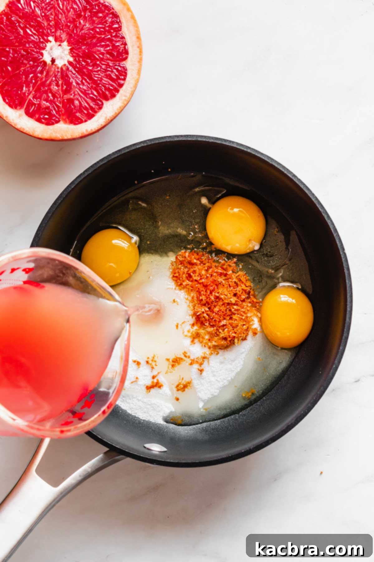 Crisp Meringue Nests with Bright Grapefruit Curd 5 Freshly squeezed grapefruit juice being carefully poured into a saucepan, ready to be combined with the other curd ingredients for cooking.