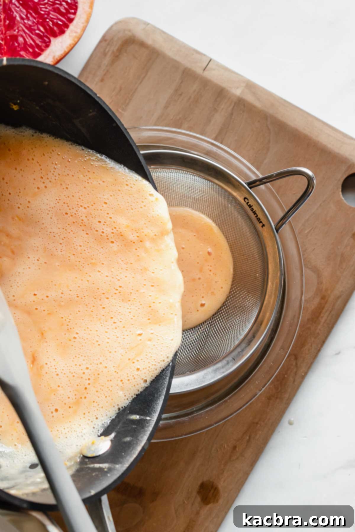 Crisp Meringue Nests with Bright Grapefruit Curd 7 The thickened grapefruit curd is meticulously poured through a fine mesh sieve into a clean bowl, ensuring a perfectly smooth and silky texture by removing any small lumps or zest.