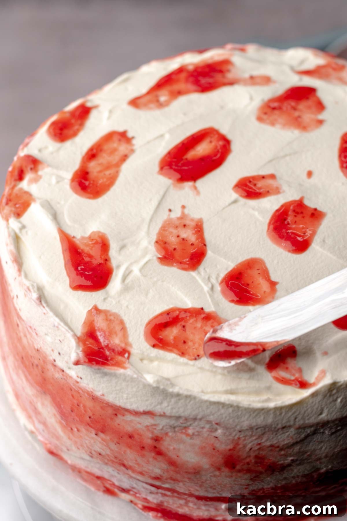 A spatula adds dollops of strawberry puree to the whipped cream to decorate.