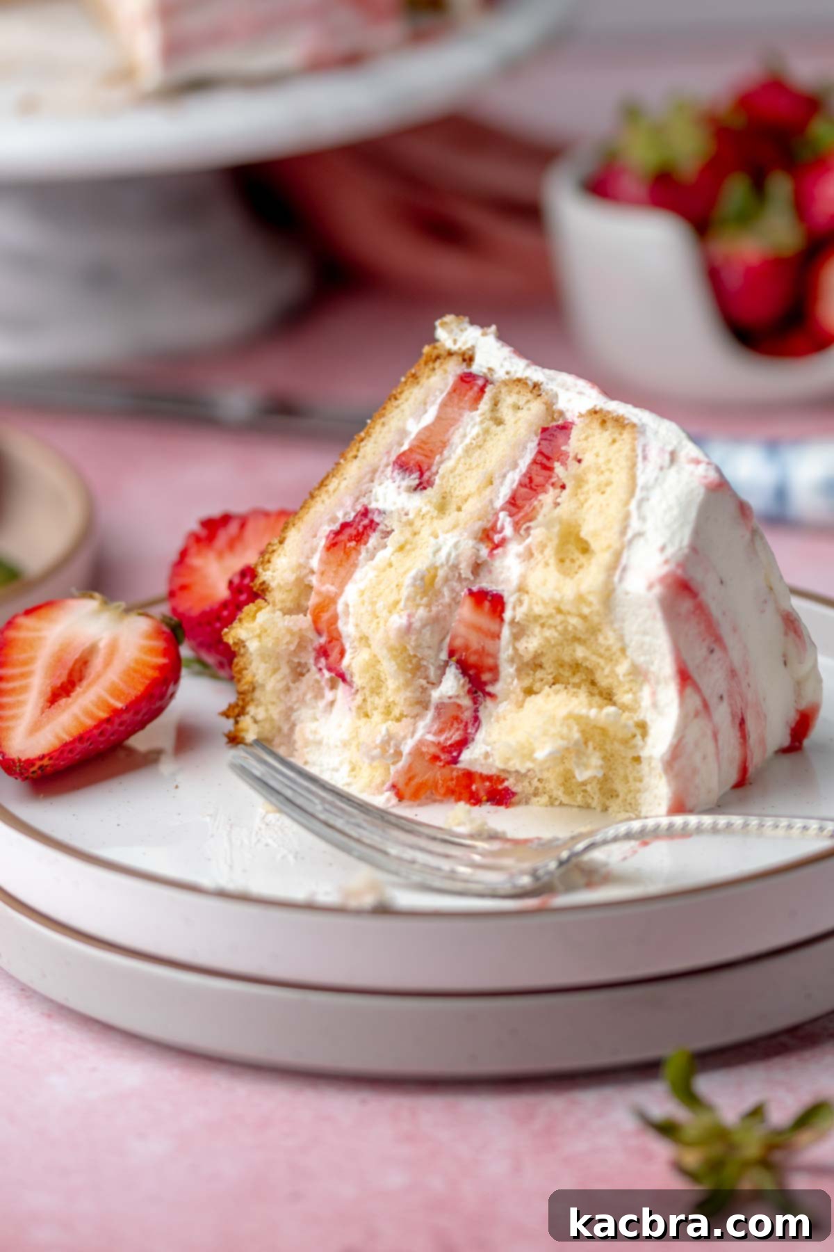 A perfectly sliced piece of strawberry shortcake cake on a plate.