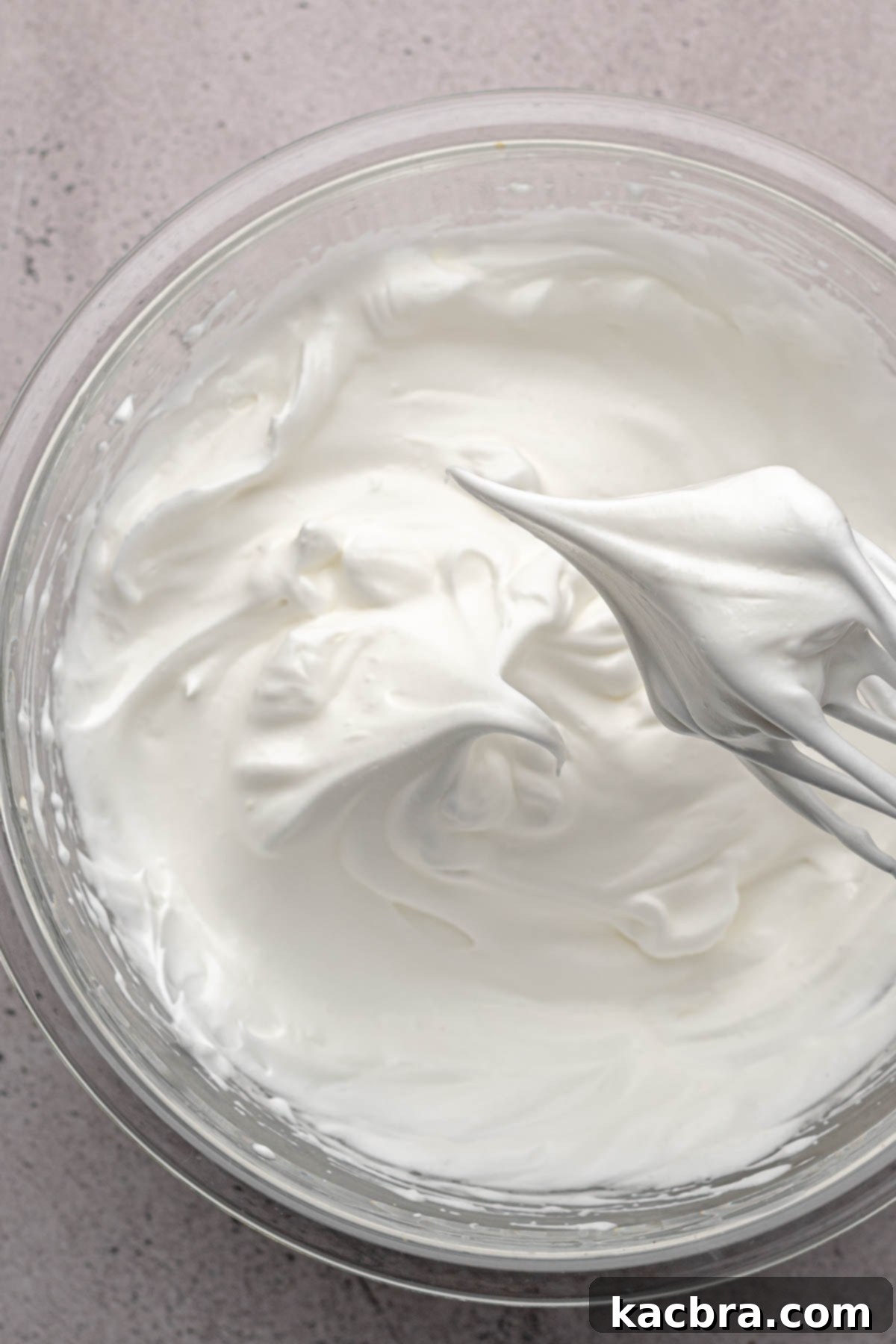 Stiff whipped egg whites on the tip of a whisk.