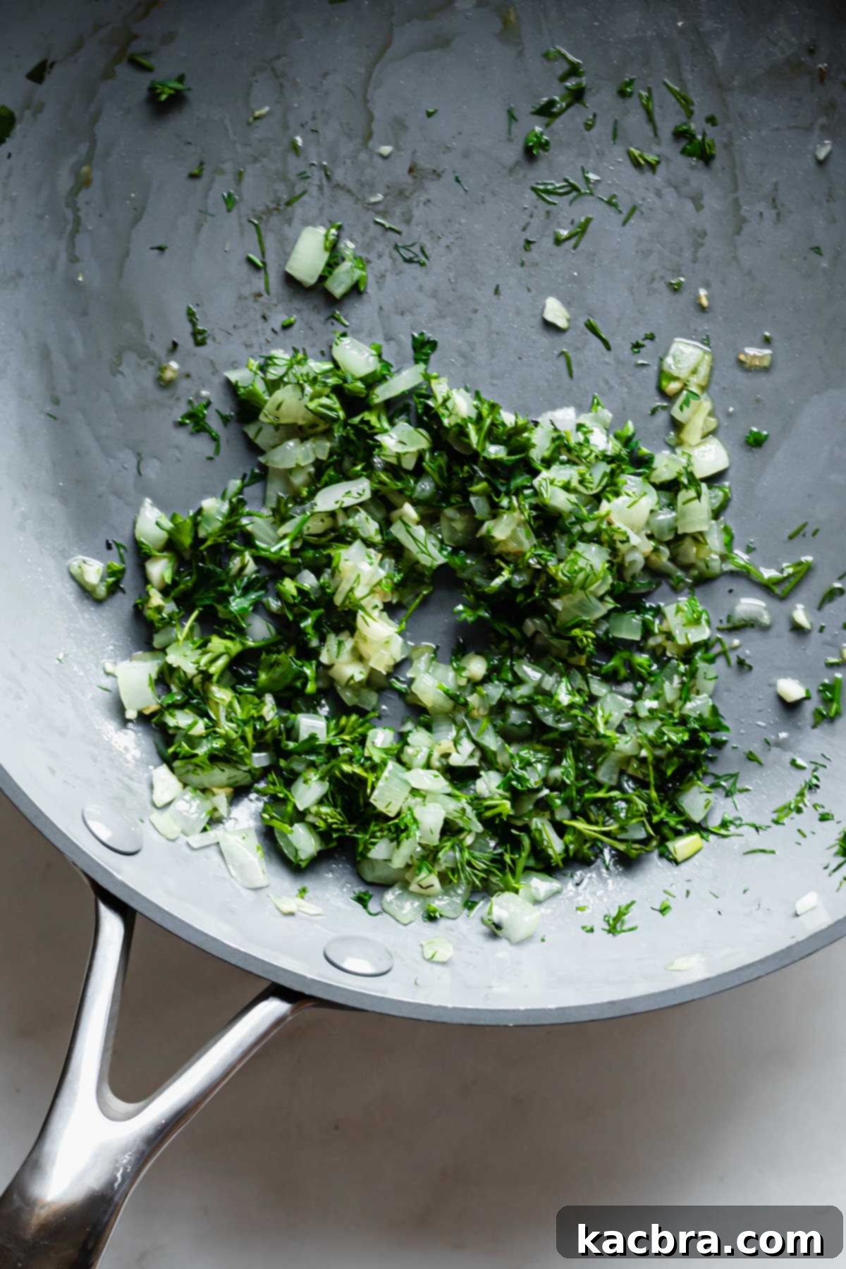 Sautéed onions, garlic, and fresh herbs in a pan, releasing their fragrances.
