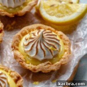 Zingy Lemon Meringue Kisses 11 Mini lemon meringue tart on a tray with fresh lemons.