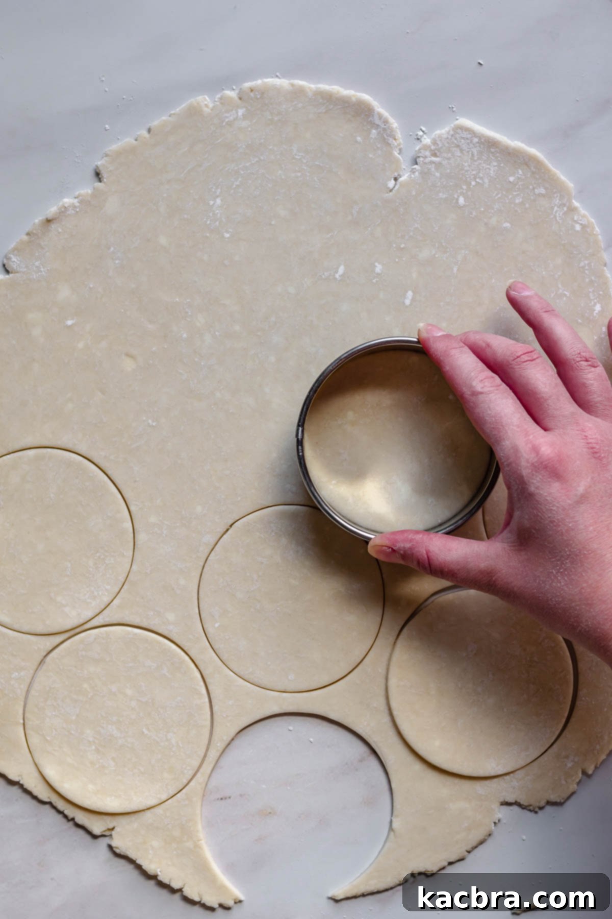 Zingy Lemon Meringue Kisses 4 Cutting rounds of dough from a rolled-out pie crust using a cookie cutter.