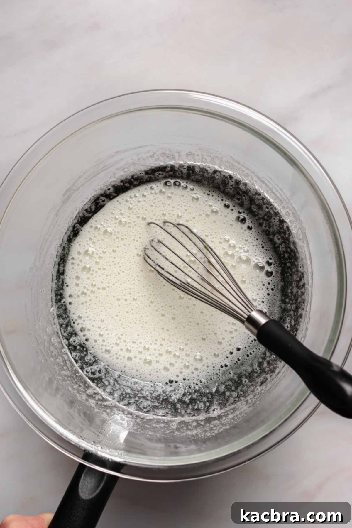 Zingy Lemon Meringue Kisses 7 Close-up of a bowl containing slightly whipped, foamy Swiss meringue mixture before stiff peaks are formed.