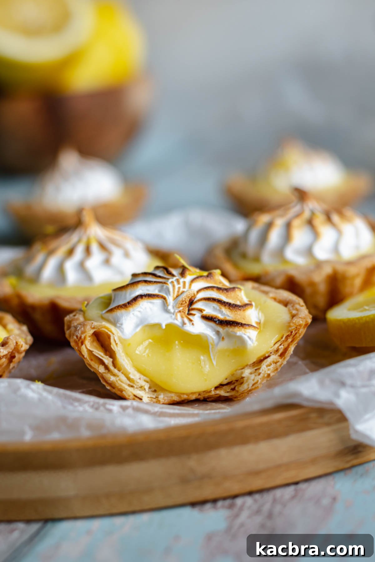 Zingy Lemon Meringue Kisses 10 Close-up of a mini lemon meringue tartlet with a bite taken out, showing the layers of meringue, lemon curd, and crust.