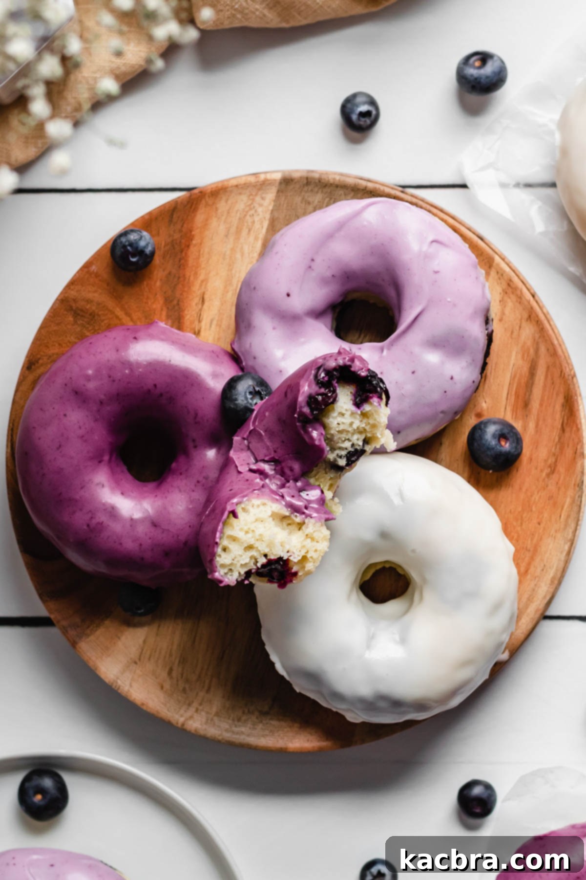 Oven-Fresh Blueberry Glazed Rounds 13 A plate of glazed blueberry donuts with a bite out of the top one.