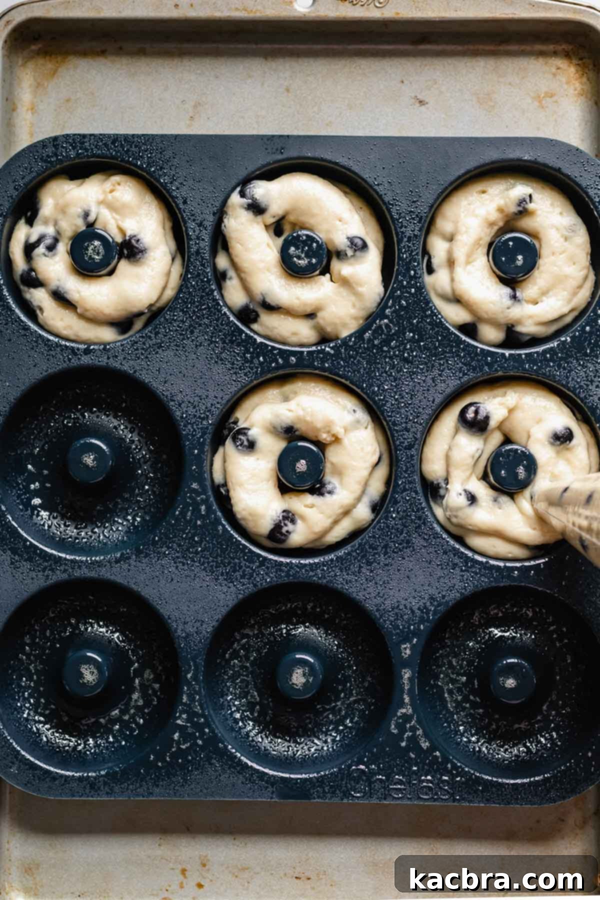 Oven-Fresh Blueberry Glazed Rounds 9 Piping batter into the donut pan.