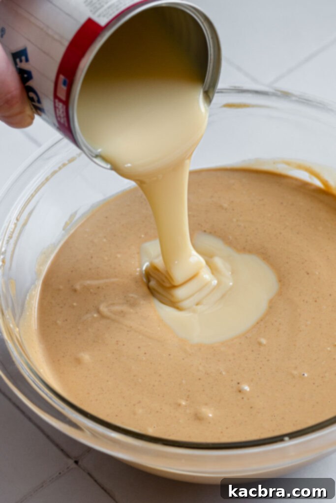 Decadent Fluffernutter Fudge 7 Sweetened condensed milk being poured into the rich peanut butter fudge mixture.
