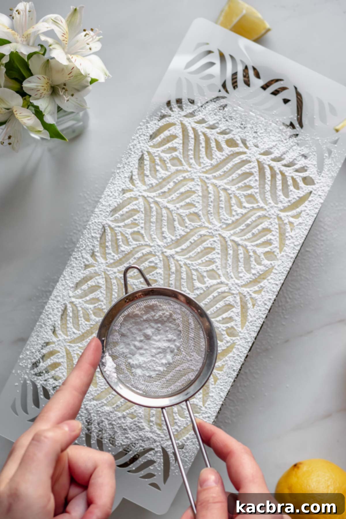 Powdered sugar being dusted through a stencil onto the tiramisu for a decorative effect.